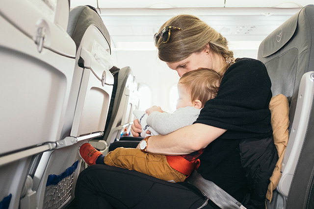 Mutter sitzt mit Baby in Flugzeug